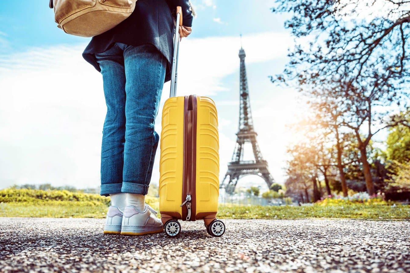 Voyageur avec une valise devant la tour Eiffel